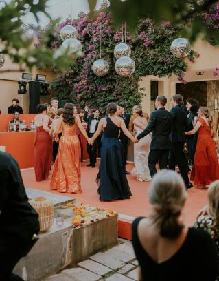 Guests enjoying an elegant outdoor wedding reception with vibrant decorations and floral backdrop.