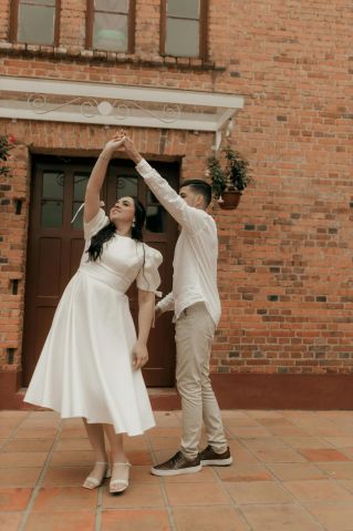 Elegant couple dancing joyfully in a brick courtyard setting.